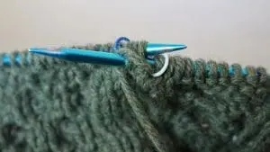 Turkoosit kutimet ja vihreä villalanka lähikuvassa