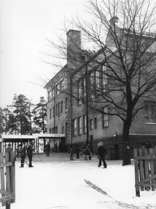 Koulun pihalla lapsia luistimet olalla.