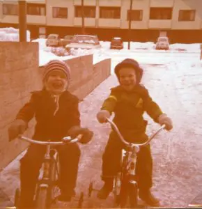 Kaksi iloista lasta pyörien selässä.