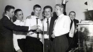 Miehet laulamassa yhteislaulua mustavalkoisessa valokuvassa
