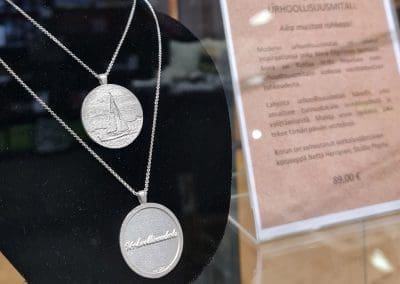 Hopeinen urhoollisuusmitali roikkuu mallinuken kaulassa