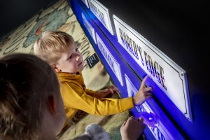 Pieni poika tutkimassa englanninkielistä Maailman reuna -kylttiä Merimonsterit-näyttelyssä