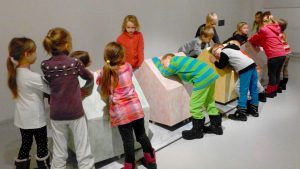 Iso ryhmä lapsia tutustumassa kosketeltavaan ja aistittavaan näyttelyyn
