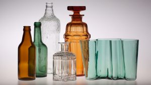 Sarja lasipulloja sekä Aalto-maljakko asetelmallisessa valokuvassa
