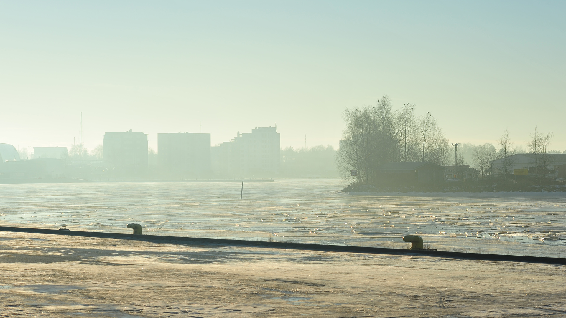 Sumuinen satama, sekä asvalttimaa että vesi jäässä ja roudassa.