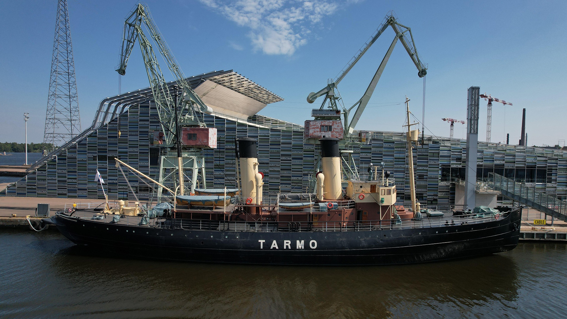 Jäänmurtaja tarmo mereltäpäin valokuvattuna, taustalla Vellamon rakennus